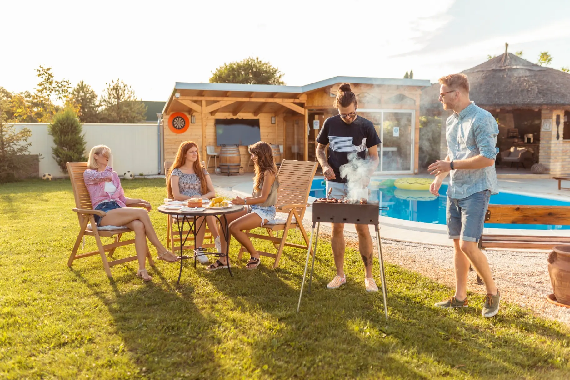 Friends grilling and entertaining poolside at a custom backyard vinyl swimming pool built by Barr Pool Builders in Utah