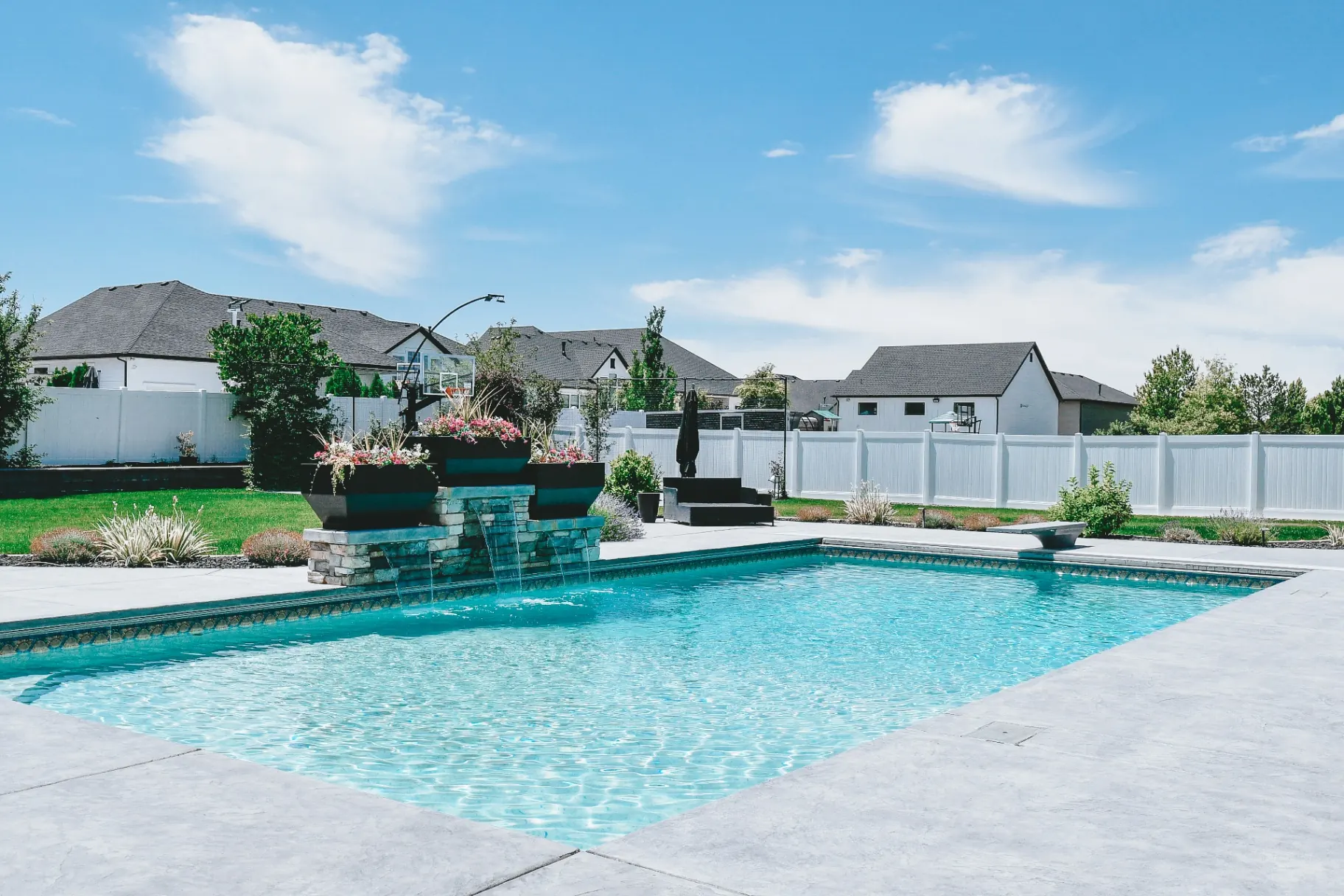 Custom backyard swimming pool oasis with cascading stone fountain water feature in Syracuse, Utah by Barr Pool Builders